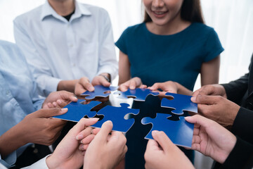 Diverse corporate officer workers collaborate in office, connecting puzzle pieces to represent...