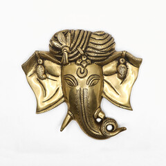 golden statue head of hindu elephant god ganesh with detailed hand carvings isolated in a white background