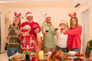 Group of happy family smiling happy celebrating christmas toasting with wine. Family member enjoy home made turkry grill dining togather at home. Christmas and New Year interior concept.