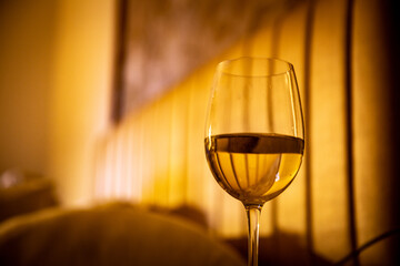Glass of White Wine by a hotel bed