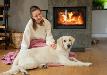 Woman sitting with dog near fireplace