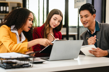 Diverse group of three professionals, two women and man, working together on design project around laptop. Product design team for industrial, working together, Asian man, African american people