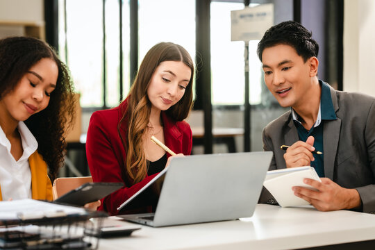 Diverse group of three professionals, two women and man, working together on design project around laptop. Product design team for industrial, working together, Asian man, African american people