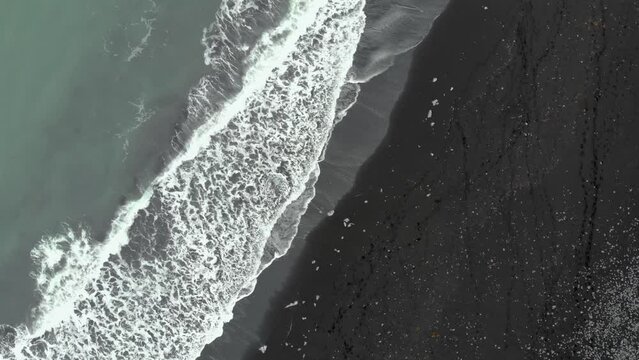 Zoom out top down of Diamond Beach in Iceland, black beach with ice