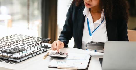 African American businesswoman, focused on her work on a laptop, possibly managing industrial...