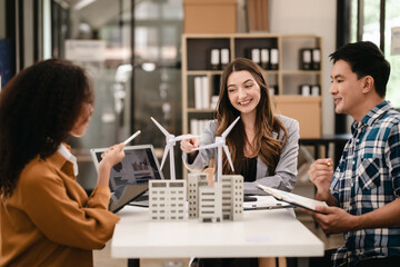 Diverse team with Asian man, African American woman, Caucasian woman discussing a clean energy city planning project with building models and solar panels.