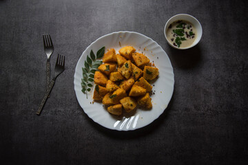 View from top of of fried idli pieces served in a white plate. Selective focus.