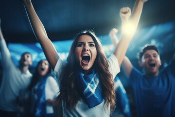 A female sports fan is happy with a group of friends, many cheering together happily and excited to watch their favorite football team. Cheering sports fans wear blue and white cheer team shirts. - obrazy, fototapety, plakaty