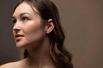 Fototapeta premium Caucasian woman with brown hair wearing natural makeup on beige background, copy space