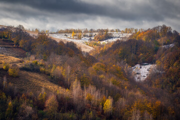 Autumn landscape with hills covered by snow in the morning.