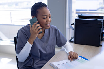 African american female doctor talking on smartphone in hospital reception