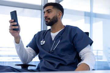 Biracial male doctor using smartphone in hospital office