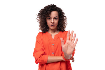 young caucasian lady with black curly hair dressed in an orange blouse asks to stop