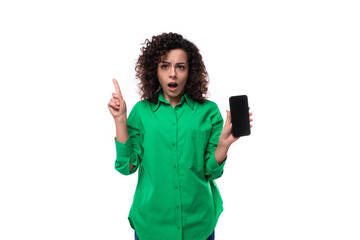 young employee of the company woman with black hair dressed in a green shirt shows the smartphone...