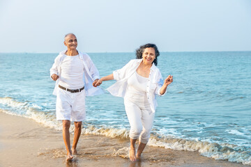 Happy romantic senior indian couple running have fun at summer beach , carefree old people, Vacations holidays, fitness health care, Aging, Mental health. Sport activity.