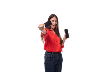 pretty confident successful young brunette business woman dressed in red blouse showing credit card and smart phone on white background with copy space