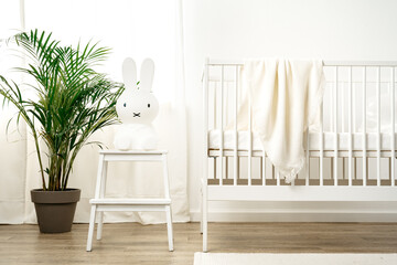 Baby wooden crib and toy rabbit in nursery room