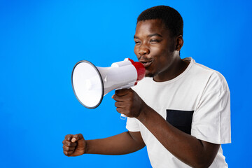 Positive african guy shouting with megaphone over blue background