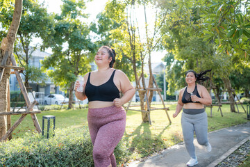 Happy plus size asian woman running in a park for health, wellness and outdoor exercise. Nature, sports and female athlete runner doing cardio workout in garden. Healthy Concept.