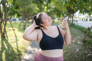 Happy plus size asian woman in fitness wear exercising in park for health, wellness and outdoor exercise. Nature, sports and female athlete runner doing cardio workout in garden.