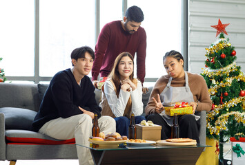 Millennial Asian Indian multinational cheerful male female friends celebrate Christmas Eve and Happy New Year holding showing presents gifts boxes in living room full decoration with Xmas tree