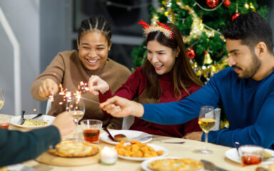 Asian Indian male female friends wears reindeer antlers headband sitting holding playing small...