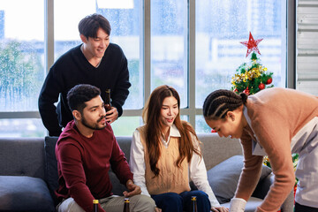 Millennial Asian Indian multinational cheerful male female friends celebrate Christmas Eve Happy New Year Chef serve hot tasty pizza pan in living room full festive decoration with Xmas tree