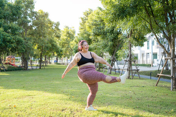 Cheerful plus size asian woman in fitness wear exercising in park. Healthy Concept.