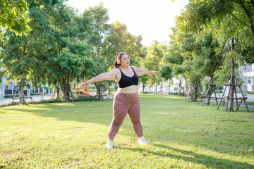 Cheerful plus size asian woman in fitness wear exercising in park. Healthy Concept.