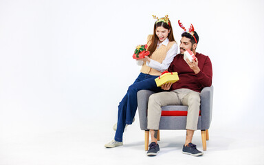 Isolated cutout studio full body shot Asian Indian male female lover couple wear reindeer antlers headband holding exchanging wrapped present gift boxes celebrating Christmas Eve on white background