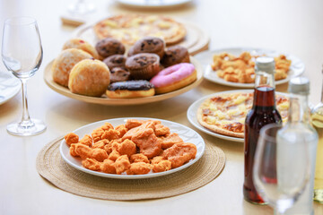 Top view closeup shot of delicious tasty yummy fast foods donuts cupcake pizza and fried chicken on wooden tray and white dish placed on table for group party celebrating Christmas eve and New Year