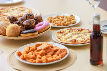 Top view closeup shot of delicious tasty yummy fast foods donuts cupcake pizza and fried chicken on wooden tray and white dish placed on table for group party celebrating Christmas eve and New Year