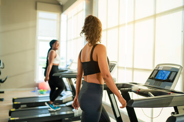 Fitness exercising in gym. Sporty woman in a sports bra doing exercise by running on treadmill...