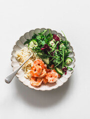 Delicious lunch - risoni pasta, shrimp and arugula, cucumber, celery salad on a light background, top view