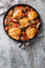 Chicken Scarpariello is a classic Italian-American dish with juicy chicken thighs, sweet Italian sausage, and a vinegary, sweet-sour sauce closeup on the plate on the table. Vertical top view