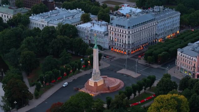 Aerial slide and pan footage of famous Freedom Monument and surrounding buildings and green public park. Riga, Latvia