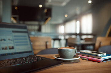 Coffree cup with laptop and mobile phone on wooden table. freelance use cafe's premises to work and communicate with customer via the computer laptop
