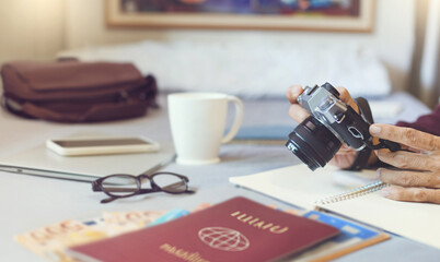 Close-up shot, hands holding camera and Necessary items for trip on bed with coffee for morning, suitcase for adventure, holiday and vacation. traveling lifestyle and freedom for journey