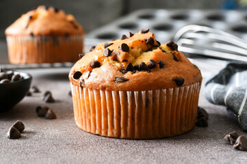 Muffin with chocolate chips on brown background. Sweet pastries.