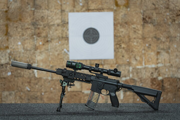 Rifle with digital night vision device and silencer in a shooting range.
