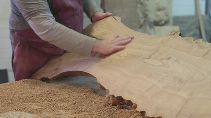 A craftsman's hand caresses the smooth surface of a timber cut, ensuring quality. The image symbolizes the hands-on approach in traditional woodworking.