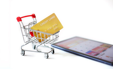 Close-up shot, credit card in small supermarket cart with digital tablet. defocus on screen show website for shopping, Concept online shopping, white background