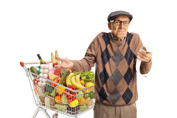Confused senior man with a shopping cart holding a receipt
