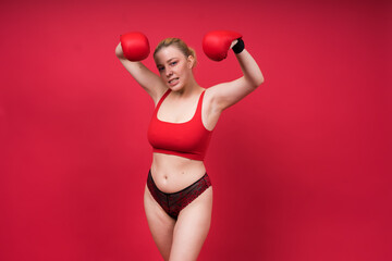 Seductive young and fit female fighter posing in gloves in studio