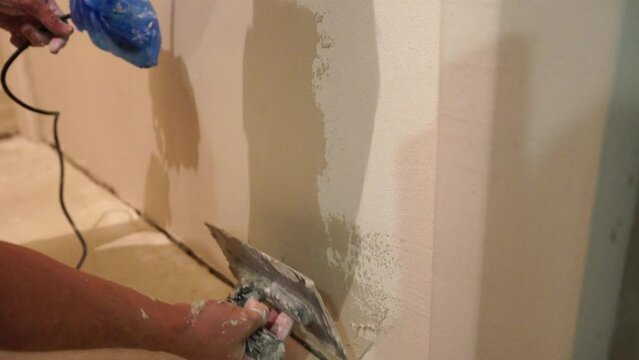 Male builder use metal spatula for putty walls, repairman filling spatula with spackling paste and covering cement wall surface. Builder leveling wall and angle Renovation work in Residential Premises