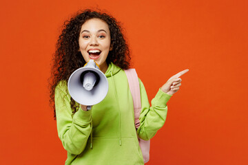 Young teen girl student of African American ethnicity wear casual clothes backpack bag hold books scream in megaphone point aside isolated on plain orange red background. High school college concept. - obrazy, fototapety, plakaty