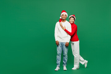 Full body cheerful lovely merry young couple man woman wear red casual clothes Santa hat posing...