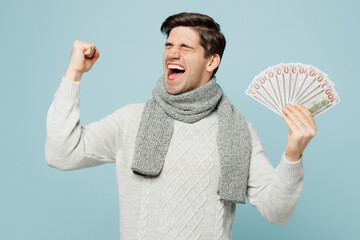 Young ill sick man in gray sweater scarf hold fan of cash money in dollar banknotes do winner...