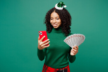 Merry little kid teen girl wears hat casual clothes posing hold mobile cell phone, fan of cash...