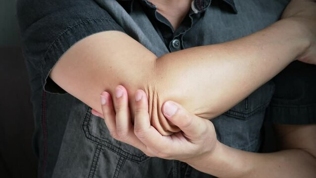 A man has pain in his elbow and tendon muscles and he relieves the pain with a massage. Health and healing concept	